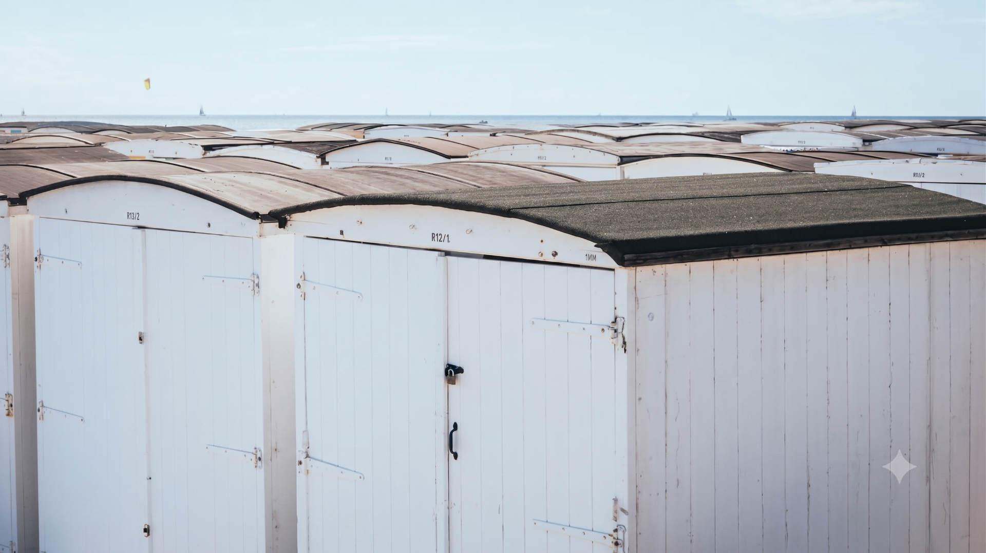 Alignement de cabanes de plage blanches au Havre — hivernage et remontage par Le Cabaniste